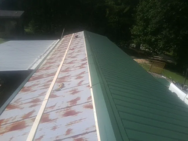Old rusted panels beside newly installed green metal roofing — Wind Damage Roof Repair by Roofing Brothers in Richfield